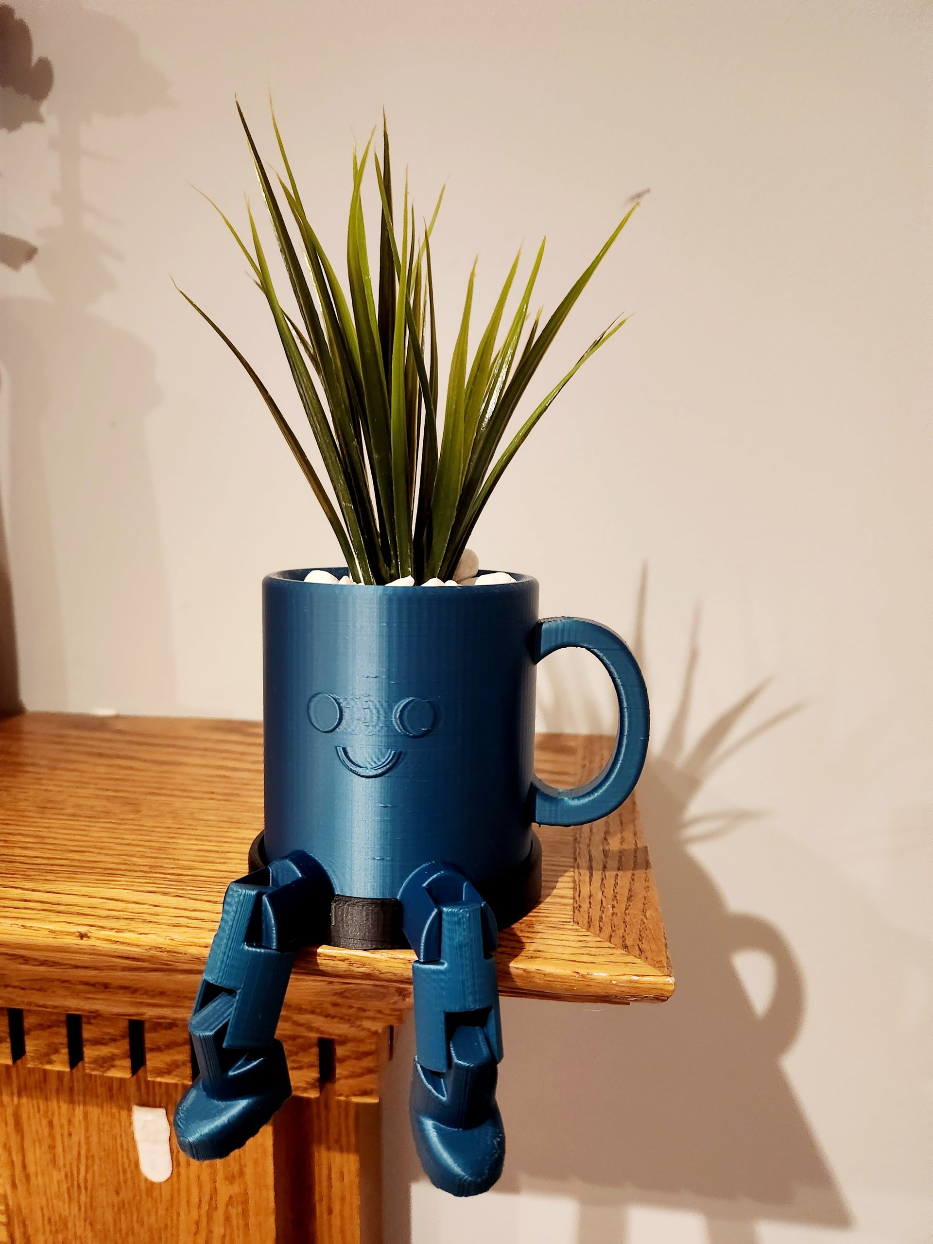 Coffee cup planter with smiley faces and legs.